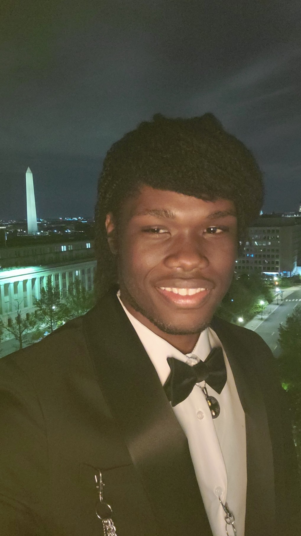Marcel Cato on a balcony in Washington, DC with the Washington Monument in the background